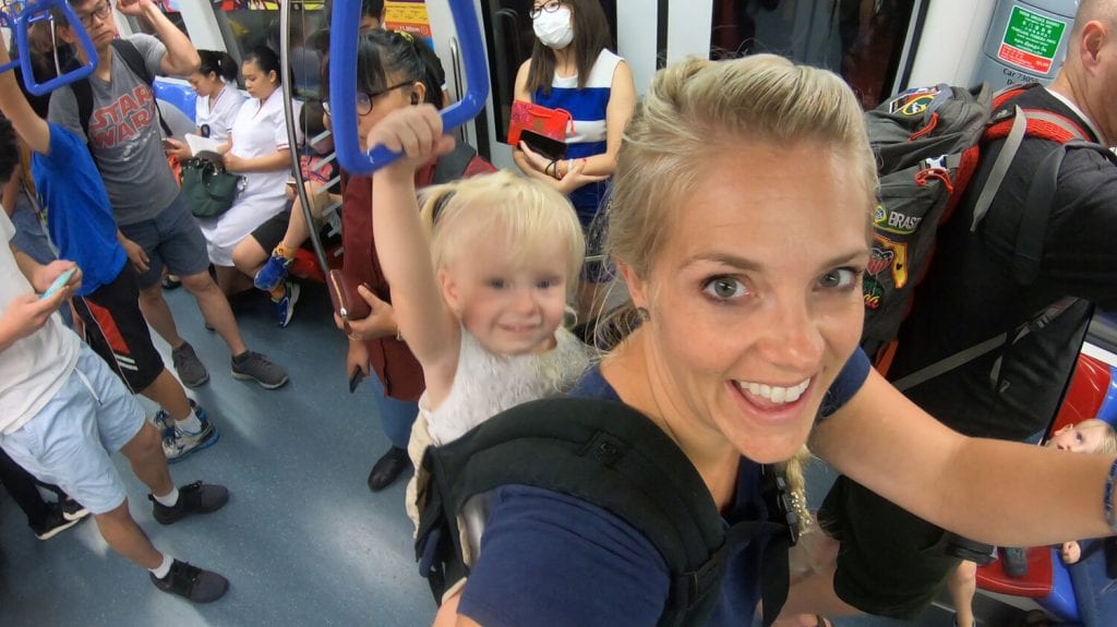 singapore travel guide- my daughter and I on a train while I am carrying her on my back