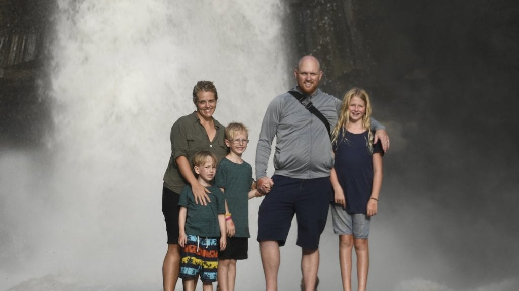 how to avoid scams- family photo in front of a waterfall