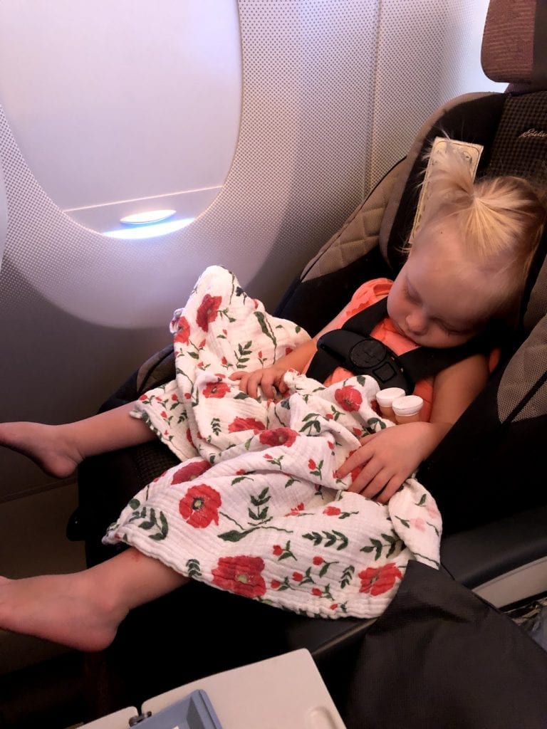 My littlest asleep in her car seat on the airplane