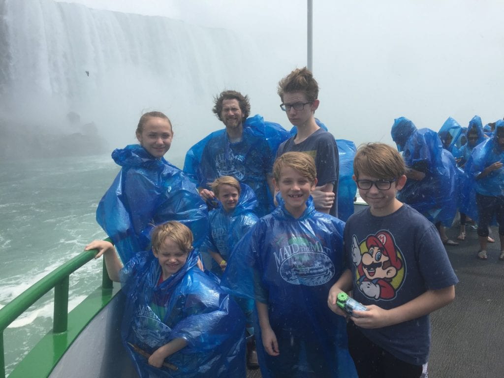 The Flory Family in front of a waterfall wearing blue ponchos in foggy weather