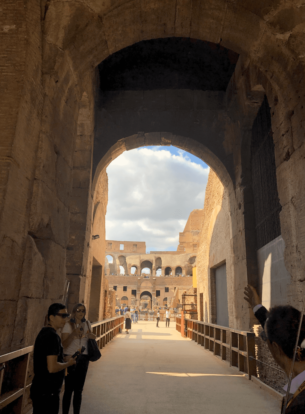 Visitors pass beneath a large stone arch into the Colosseum.