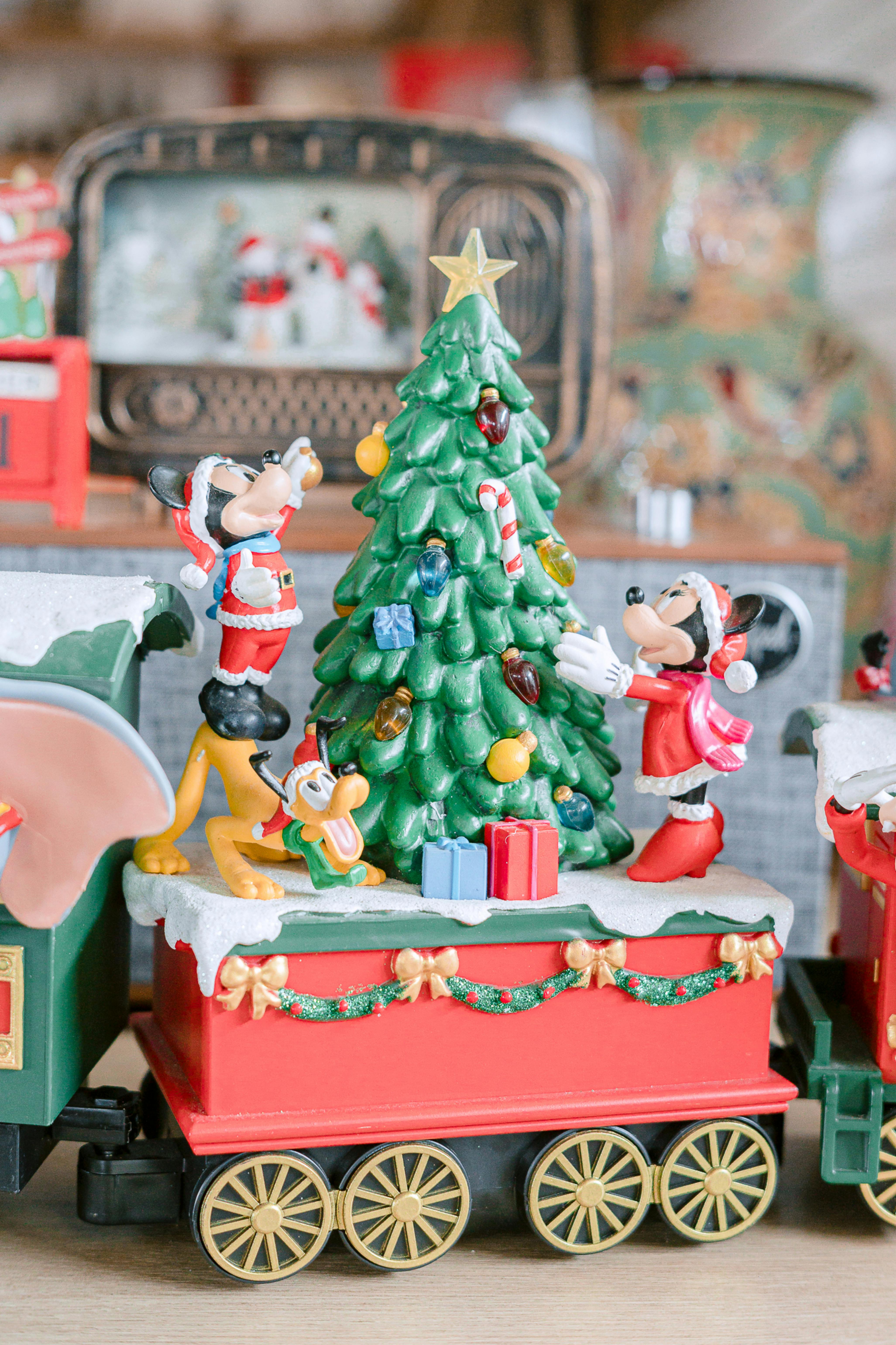 Christmas decoration featuring Mickey, Minnie, and Pluto putting up the Christmas tree while standing on a railroad track.