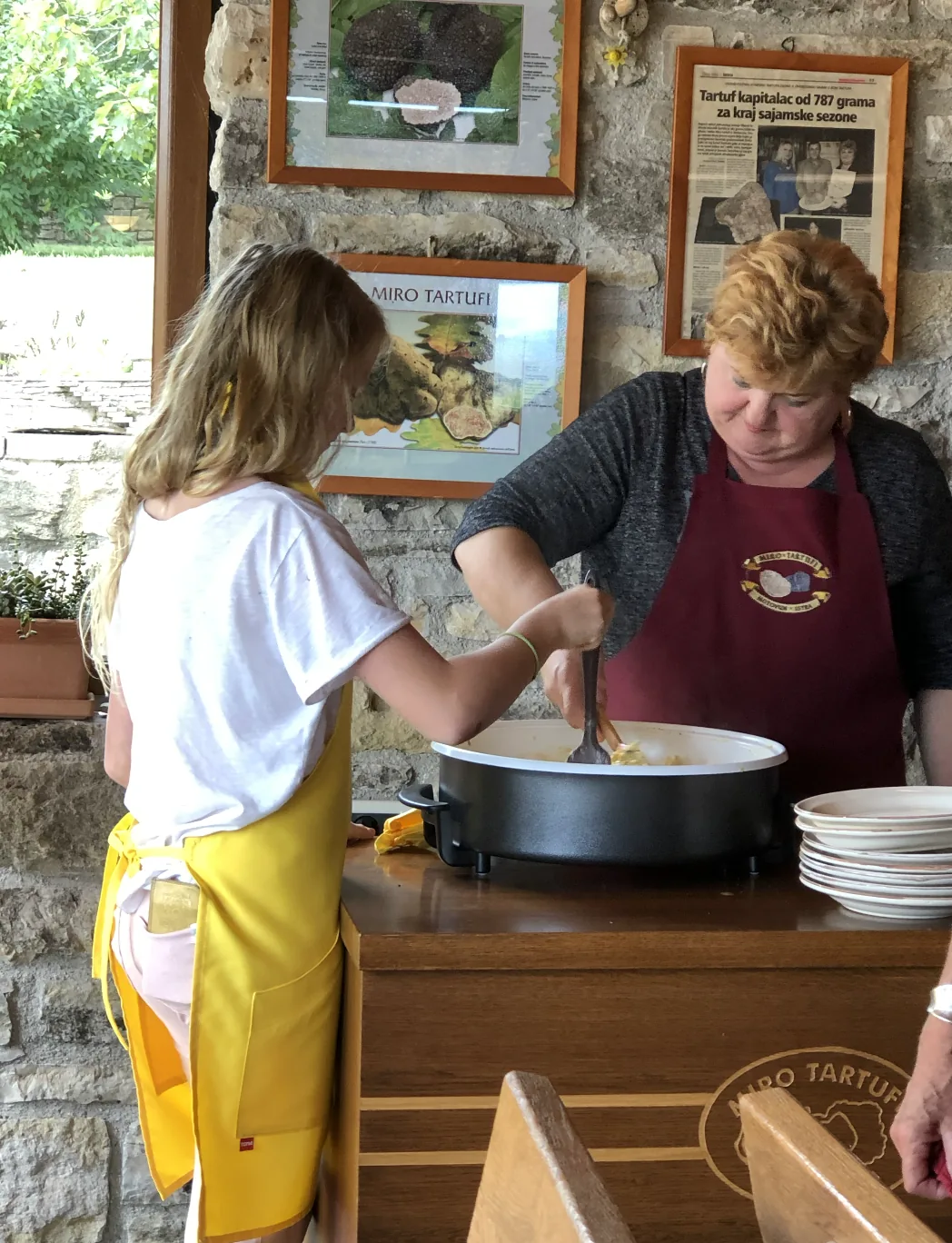A child helps stir eggs in a pot during a cooking demonstration.
