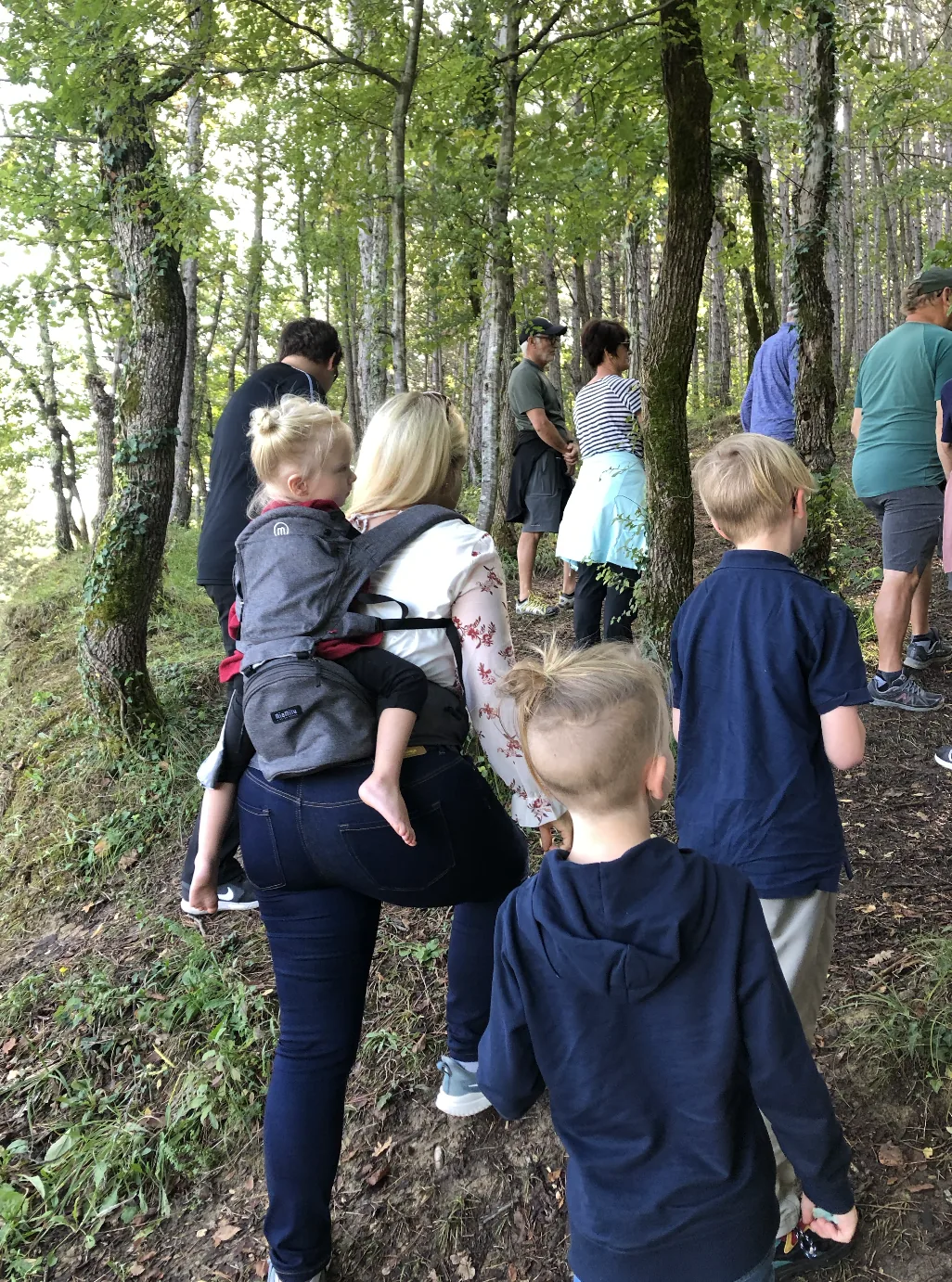 A family follows a guide through a wooded trail during a truffle-hunting outing.