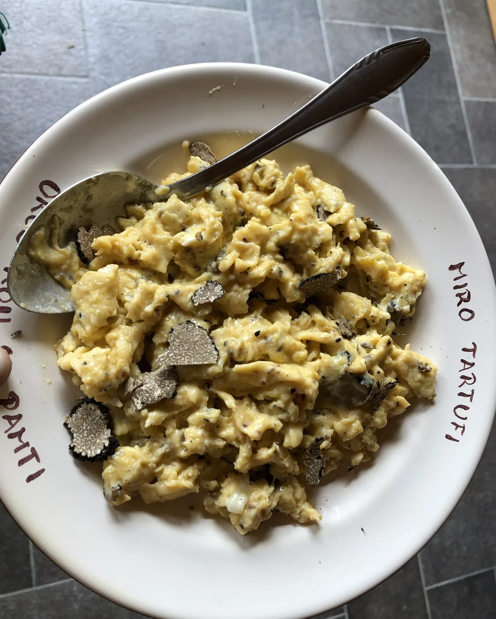 Scrambled eggs topped with shaved truffle on a plate.