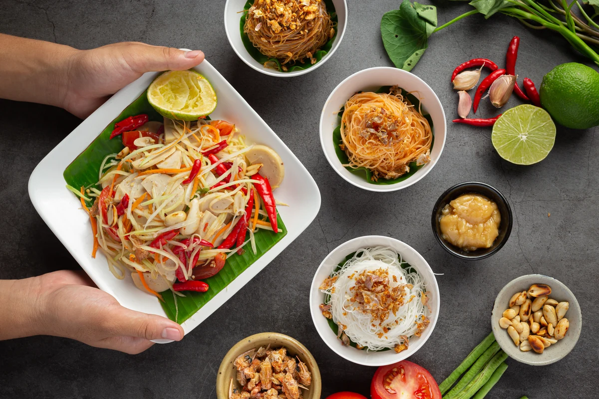A meal of Thai dishes, including papaya salad and rice.