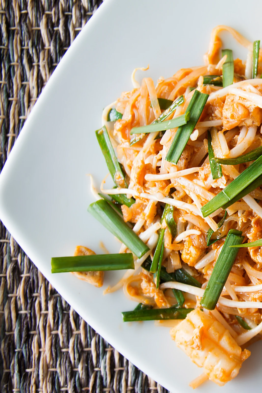 A plate of pad Thai with green onions.