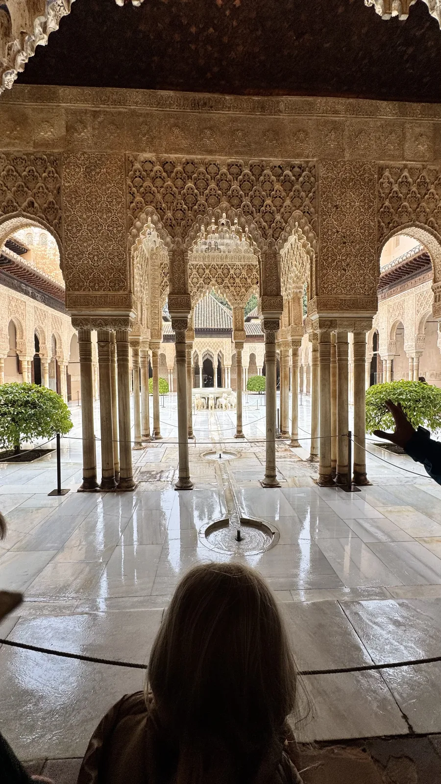 Child seen from behind in a columned courtyard with a central fountain.
