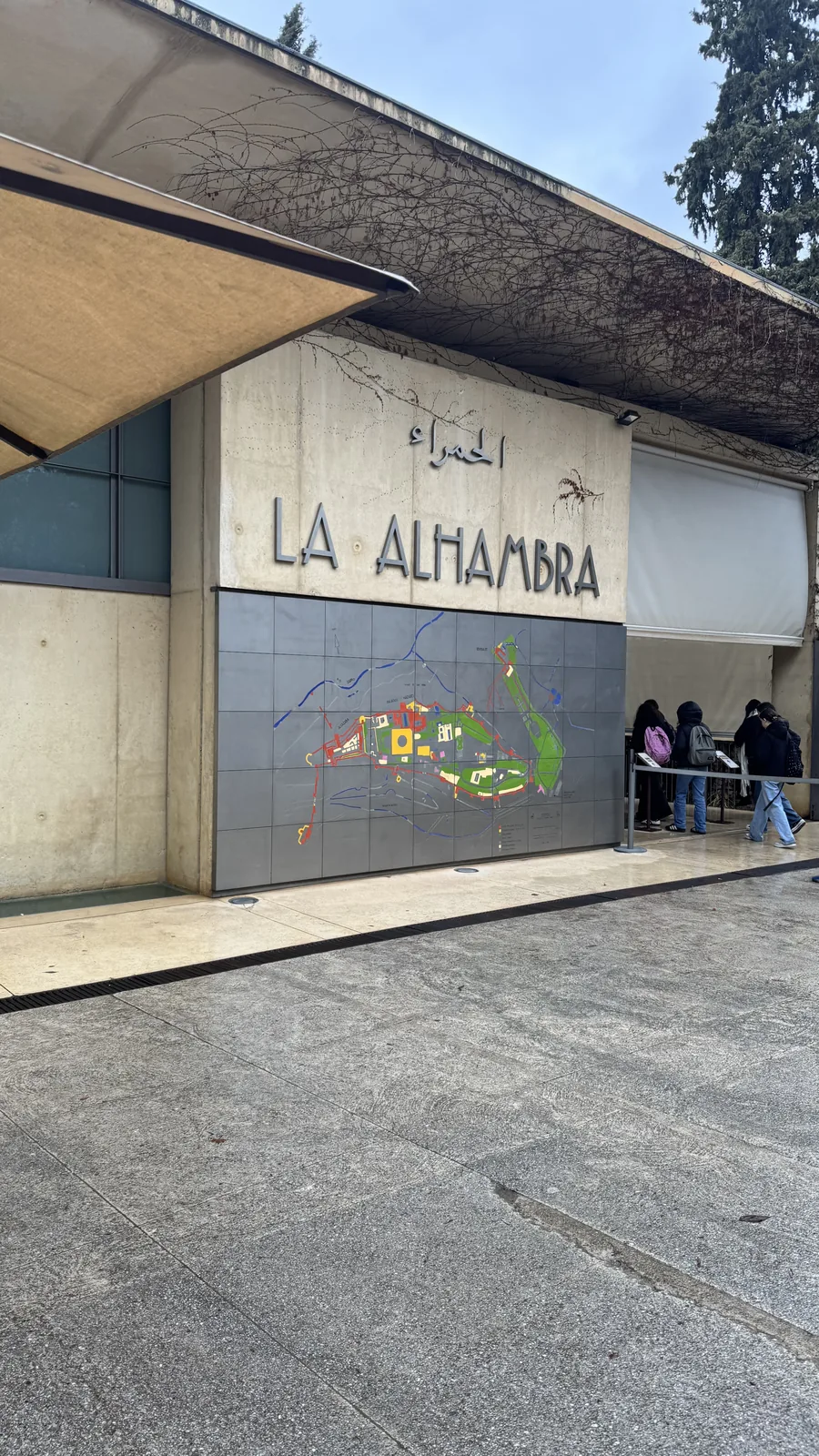 Facade with the LA ALHAMBRA sign above glass entrance doors and visitors outside.