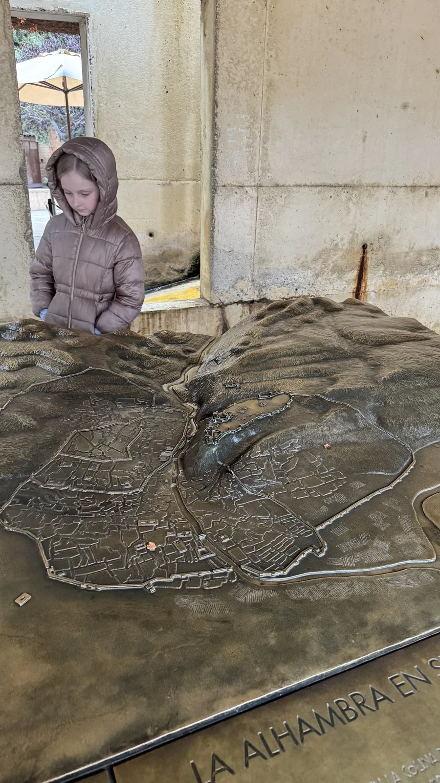 A child looking down at a relief model labeled La Alhambra.