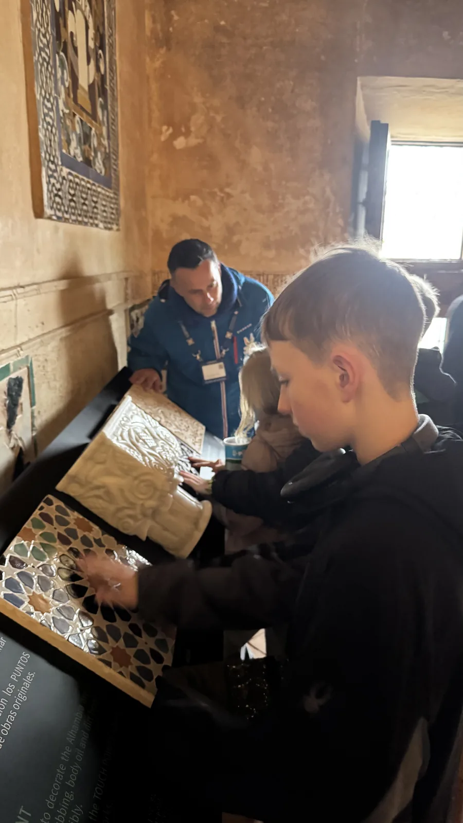 A man and child leaning over a detailed tiled map or model on a table.