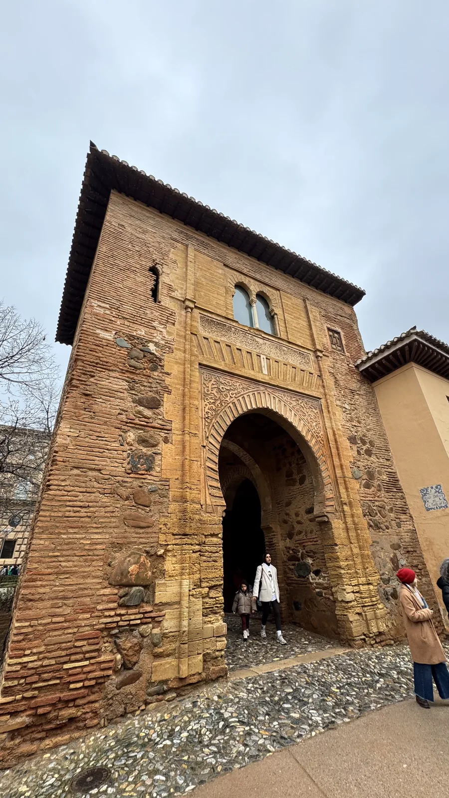 Visitors entering through a tall stone archway in a brick tower.